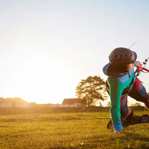 Pratiquant de kite sur landboard dans l'herbe