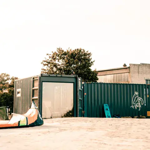 Containers de l'école et kite posé sur le sable