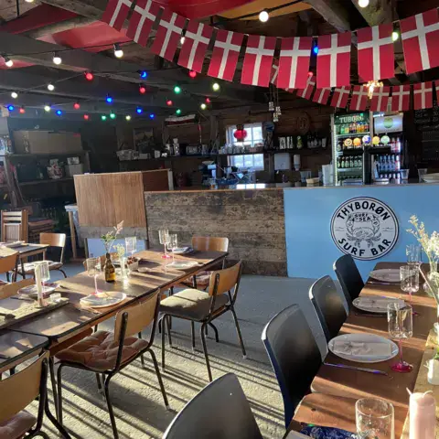 Salle du bar, avec des tables dressées et des guirlandes de drapeaux