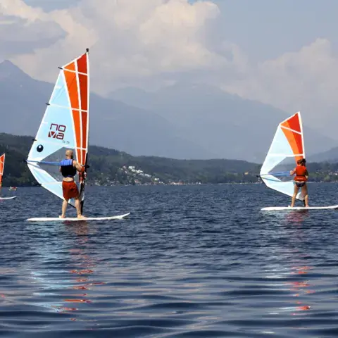 Deux windsurfeurs sur le lac, montagnes en arrière-plan