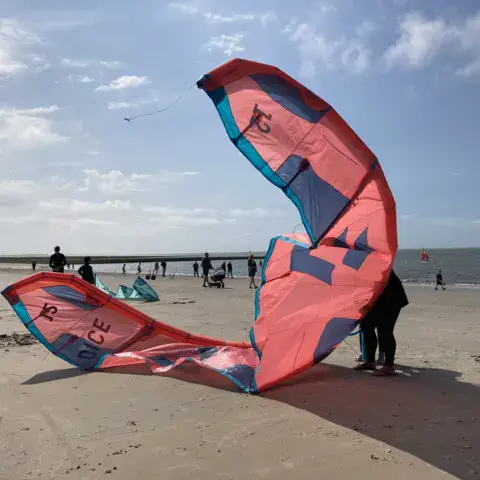 Grande aile de kite déployée sur la plage