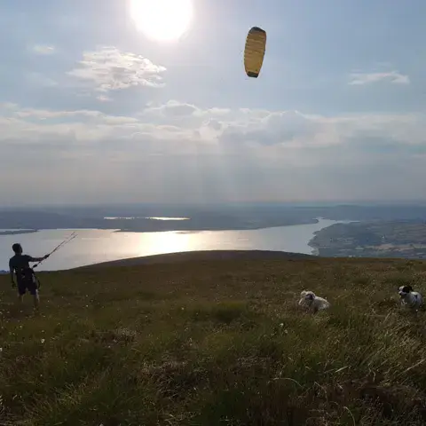 Kitesurfeur sur une colline, avec un plan d'eau en contrebas