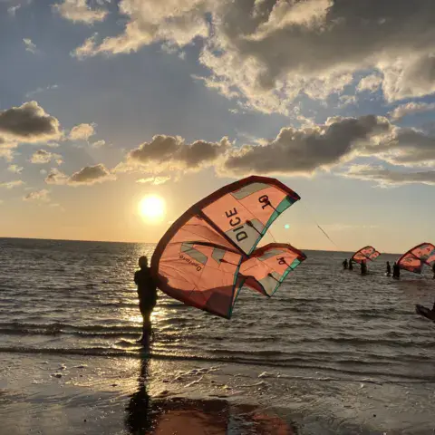 Aile de kite au coucher du soleil, au bord de l'eau
