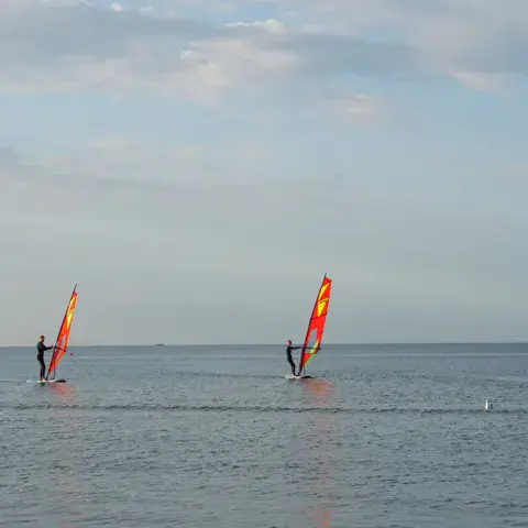 Trois windsurfeurs sur l'eau
