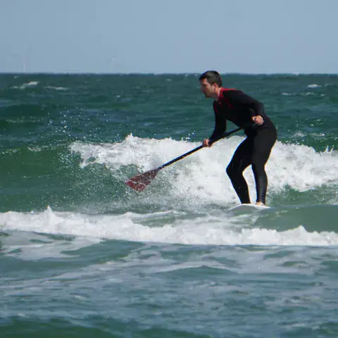 Pratiquant de stand up paddle dans les vagues
