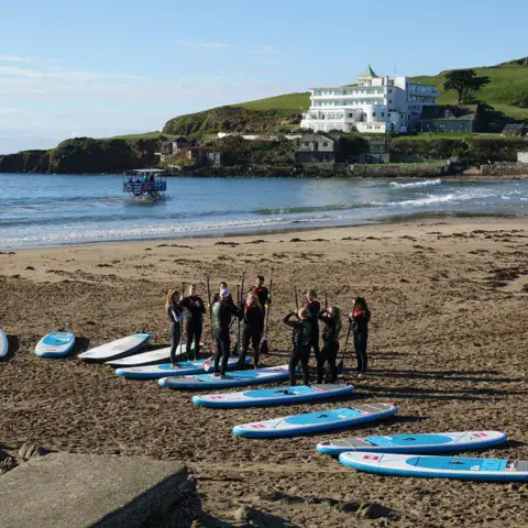 Groupe devant des planches de paddle alignées sur la plage