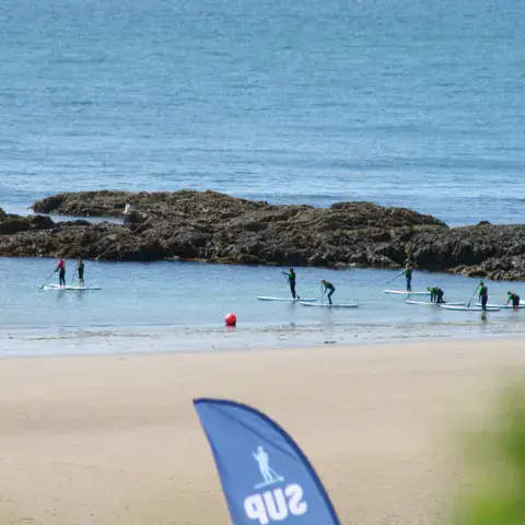 Séance de paddle dans l'eau peu profonde, près de rochers