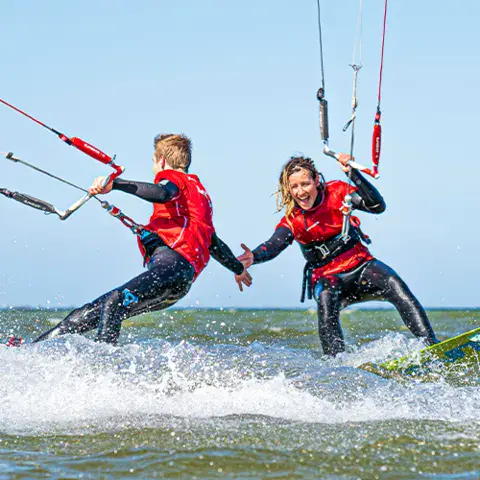 Deux kitesurfeurs en action dans l'eau peu profonde