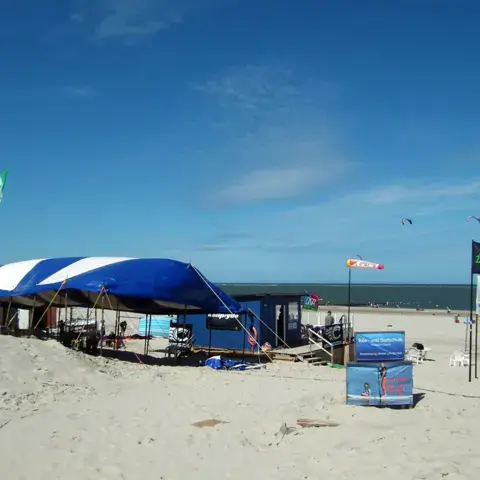 Tente et cabane sur la plage, drapeau flottant