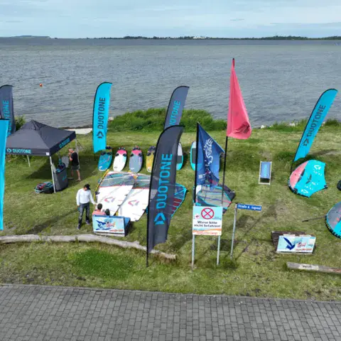 Stand de matériel avec drapeaux et tonnelle près de l'eau