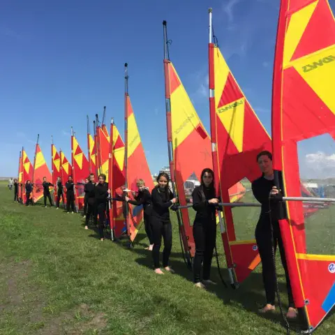 Voiles de windsurf alignées sur l'herbe