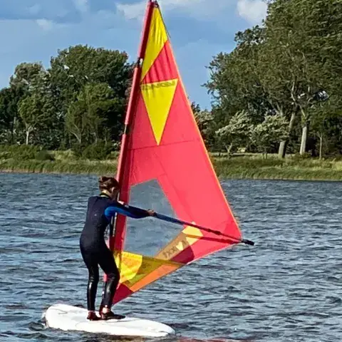 Une élève de windsurf sur sa planche