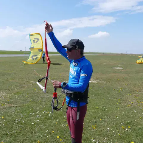 Un moniteur règle une barre de kite sur la pelouse
