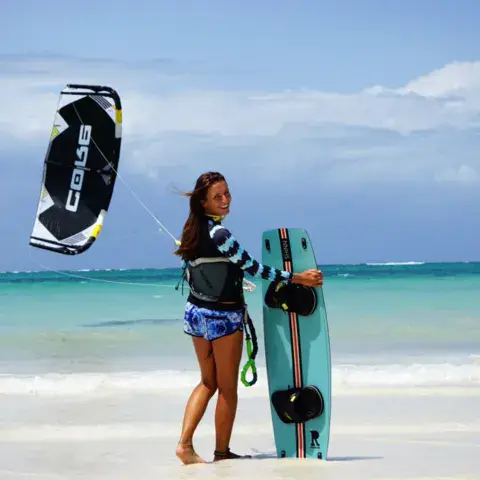 Élève de kitesurf avec sa planche et son aile sur la plage