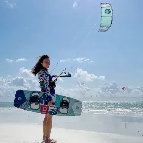 Kitesurfeuse avec sa planche sur la plage