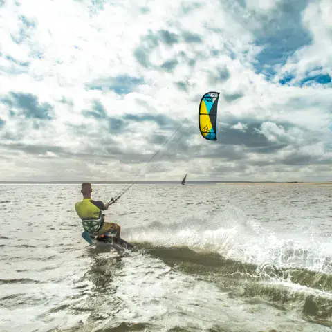 Kitesurfeur dans les vagues sous un ciel nuageux