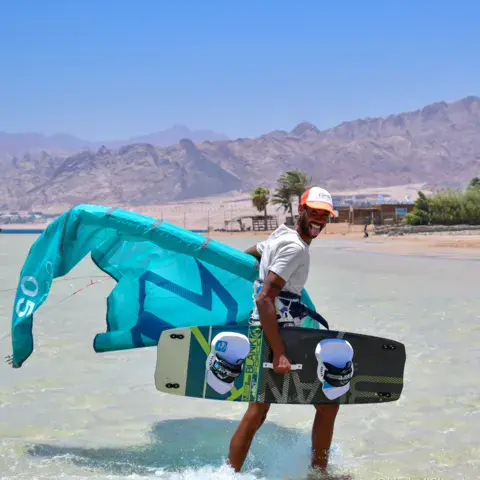 Un kiteur sort de l'eau avec son kite et sa planche