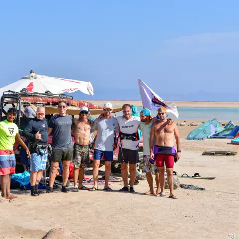 Un groupe de kiteurs autour de la Jeep sur la plage