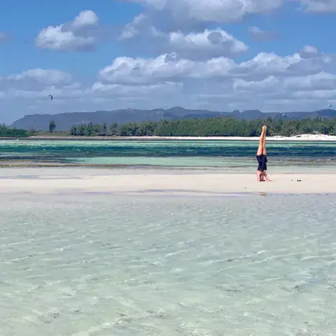 Plage de sable blanc et eau peu profonde devant l'hôtel