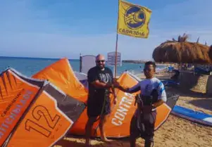 Deux personnes se serrent la main sur la plage, parmi les kites