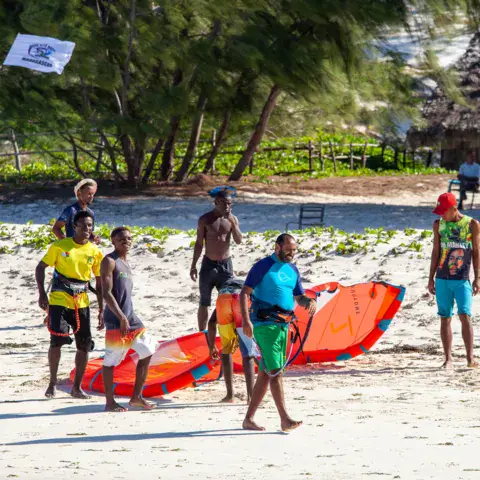 Sur la plage, autour d'une aile de kite