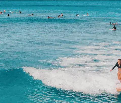 Surfeuse sur une vague, d'autres surfeurs au large