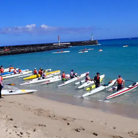 Pirogues et surfskis alignés sur la plage
