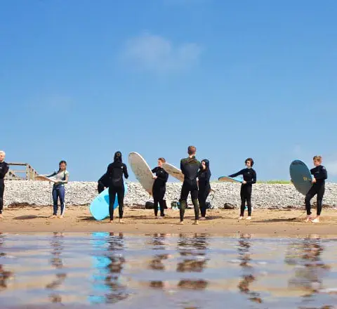 Un groupe d'élèves avec leurs planches sur la plage