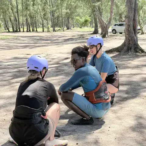 Briefing au sol entre la monitrice et deux élèves avant la mise à l'eau