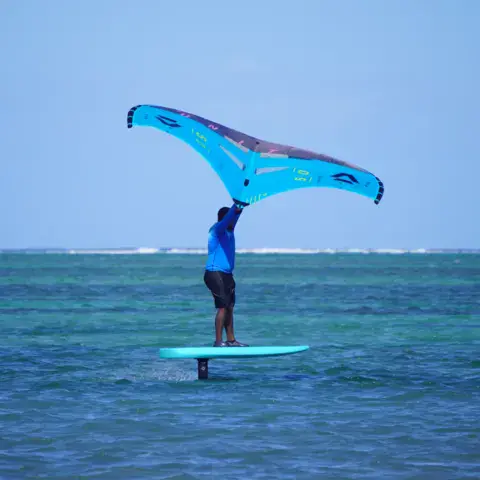 Un rider en wing foil sur l'eau turquoise