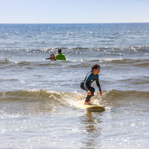 Un jeune surfeur debout sur sa planche dans les vagues