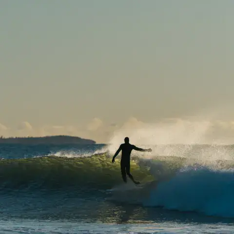 Un surfeur en combinaison sur une vague