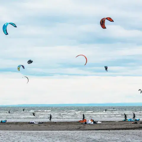 Plusieurs ailes de kite dans le ciel au-dessus d'une plage