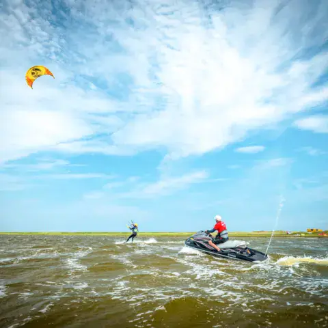 Instructeur en motomarine supervisant un kitesurfeur dans la lagune