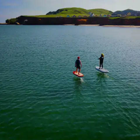 Deux pratiquants sur des planches au large des falaises rouges des Îles