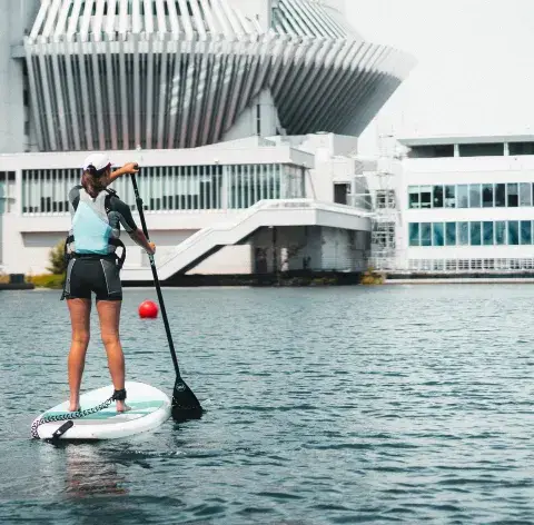 Pagayeuse en paddle devant des bâtiments au bord de l'eau