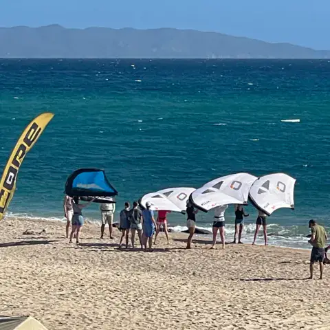 Groupe d'élèves avec des ailes de wing sur la plage