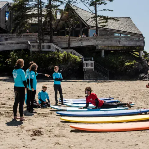 Élèves et moniteurs sur la plage avec les planches