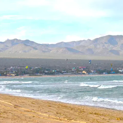 Plage de la baie avec des kites et la sierra en arrière-plan