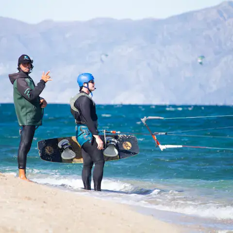 Moniteur et élève au bord de l'eau avec des planches de kite