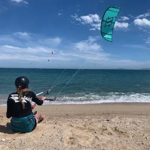 Élève de kite assise sur la plage