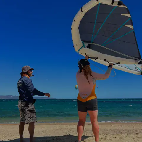 Moniteur et élève avec une aile de wing sur la plage