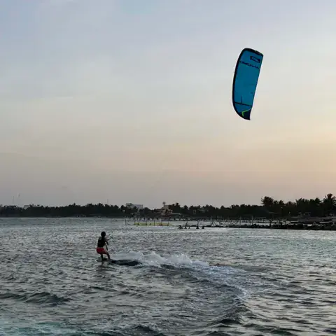 Kitesurfeur au crépuscule dans l'eau peu profonde