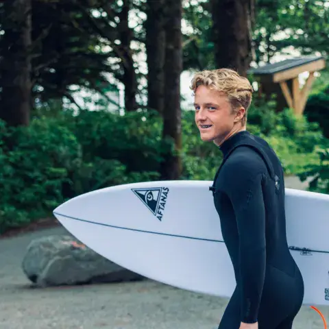 Surfeur en combinaison avec sa planche