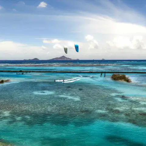 Kitesurfeurs sur un plan d'eau plat entouré de récifs