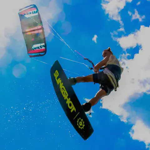 Kitesurfeur en plein saut sous un ciel bleu