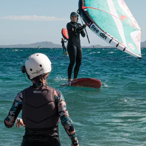 Élève de wing foil avec une moniteuse dans l'eau