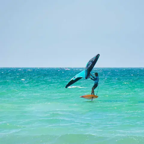 Rider de wing foil sur une eau turquoise