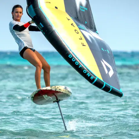 Rideuse en wingfoil sur l'eau turquoise