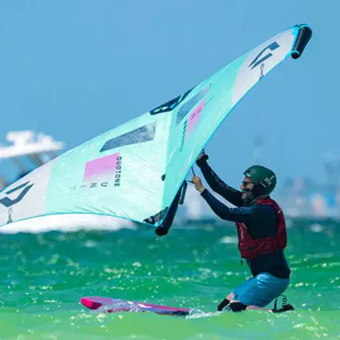 Rider de wing foil à genoux sur sa planche dans l'eau